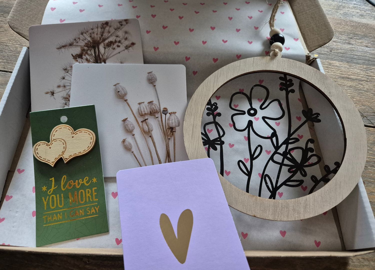 Doos met wenskaarten, wanddecoratie en een hartvormig label. De artikelen zitten in een doos met een hartjespatroon.