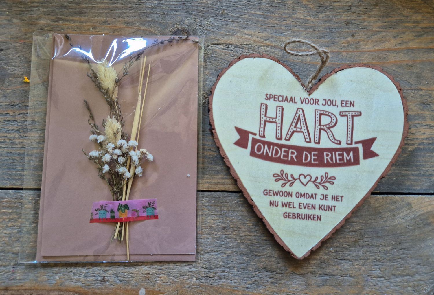 Cadeauverpakking met een houten hartje als ornament en een kaartje met gedroogde bloemen.