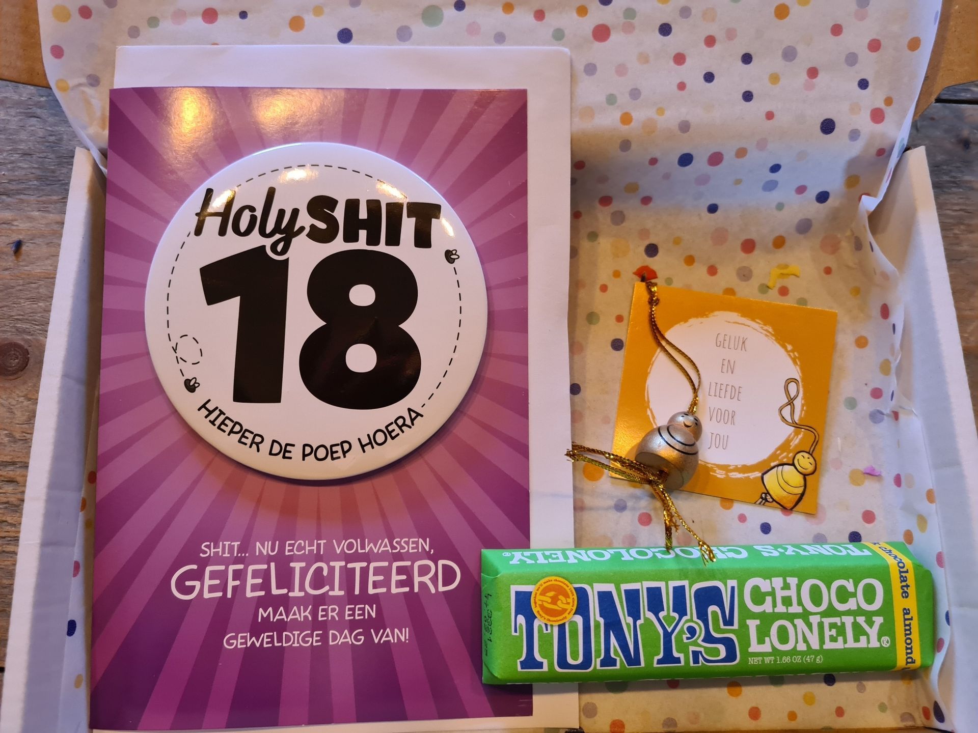 Doos met cadeautjes voor een 18e verjaardag: kaart, chocolade en bedeltje. Tekst bevat onder andere 