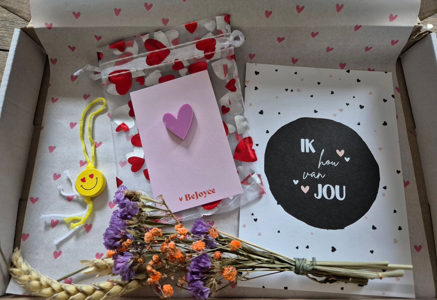 Doos met Valentijnscadeautjes: bloemen, kaart, sleutelhangertje met smiley, tasje met hartjesprint, kaartje met de tekst 