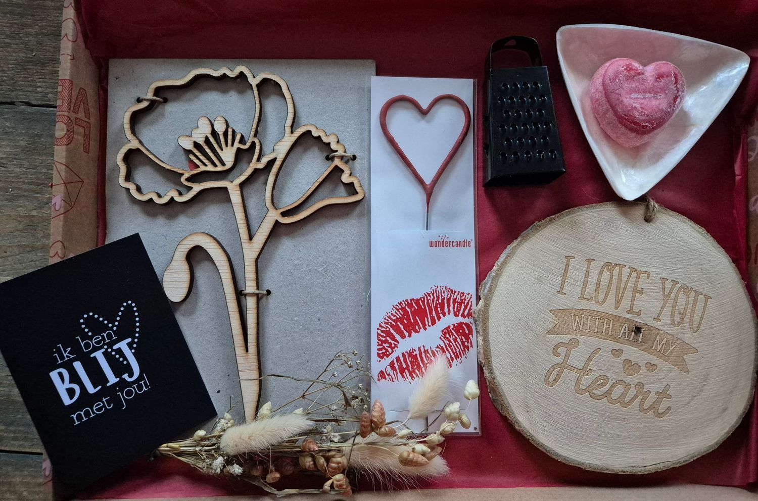 Valentijnsdagcadeauverpakking met houten klaproos, hartvormige versieringen, geraspte zeep en een 'Ik hou van jou'-bordje.