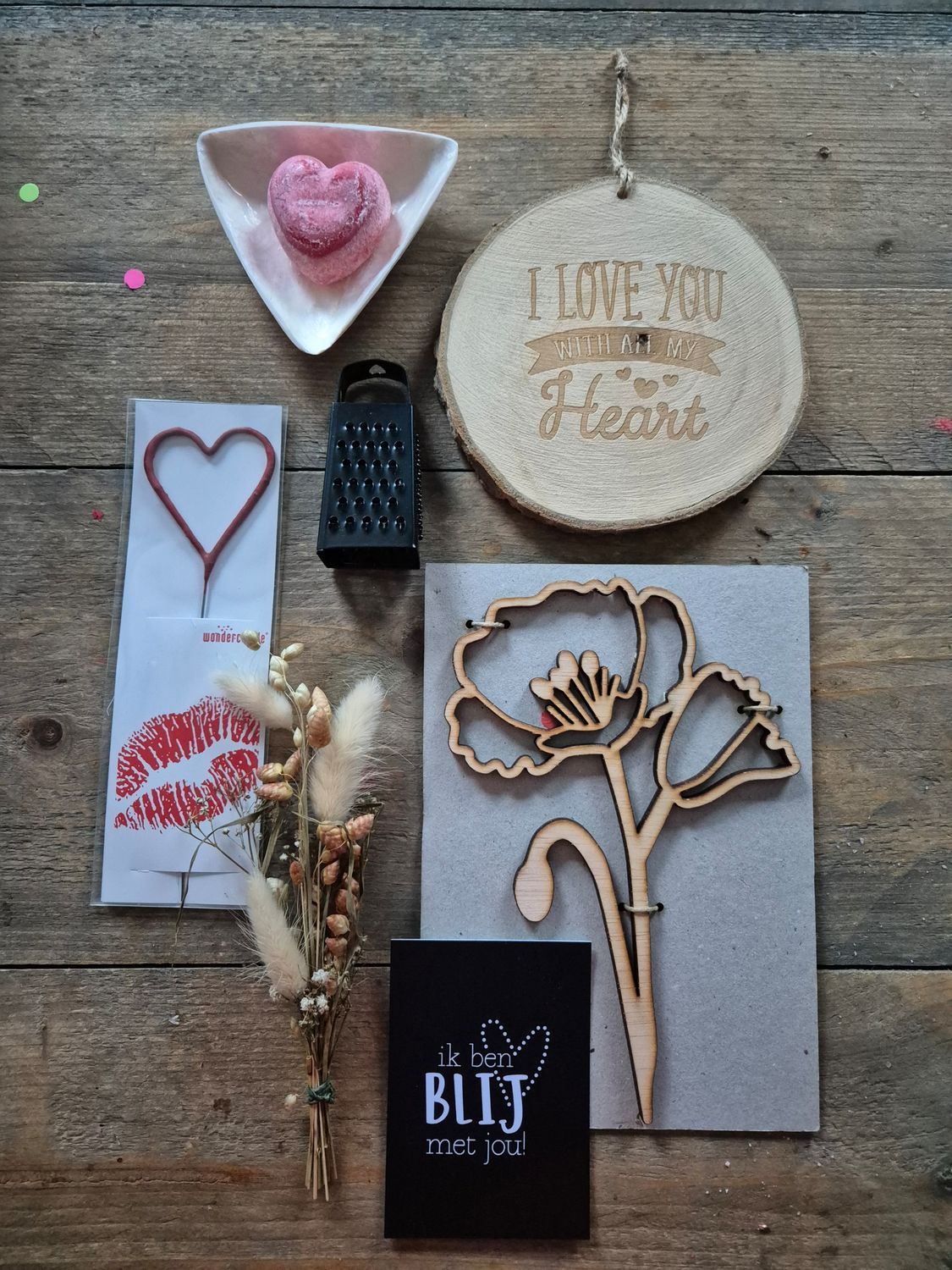 Valentijnsdagcadeauverpakking met houten klaproos, hartvormige versieringen, geraspte zeep en een 'Ik hou van jou'-bordje.