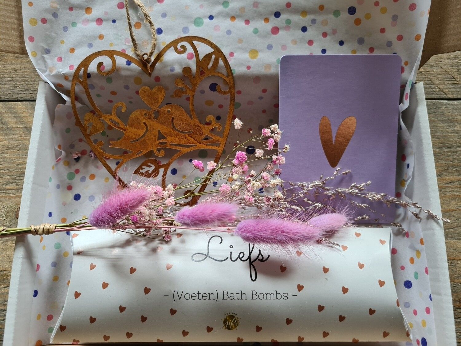 Doos met hartvormige versiering, paars karton, roze bloemen en een rol met de tekst 