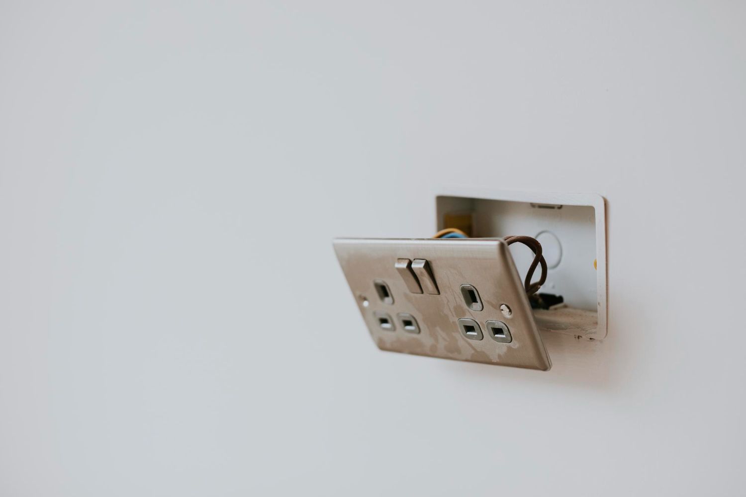 A light switch is being installed on a white wall.
