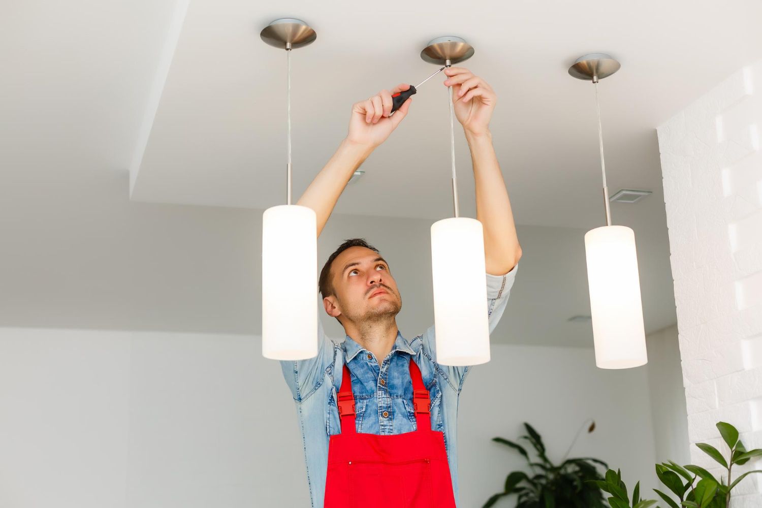 A man is fixing a ceiling light with a screwdriver.