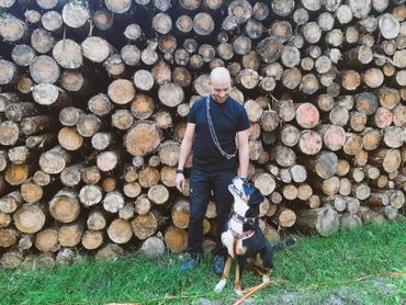 Mann mit Hund am Holzstapel
