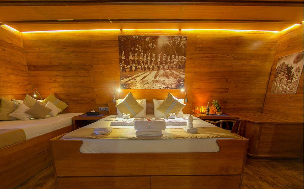 Wooden hotel room with bed, sofa, and artwork, bathed in warm lighting.