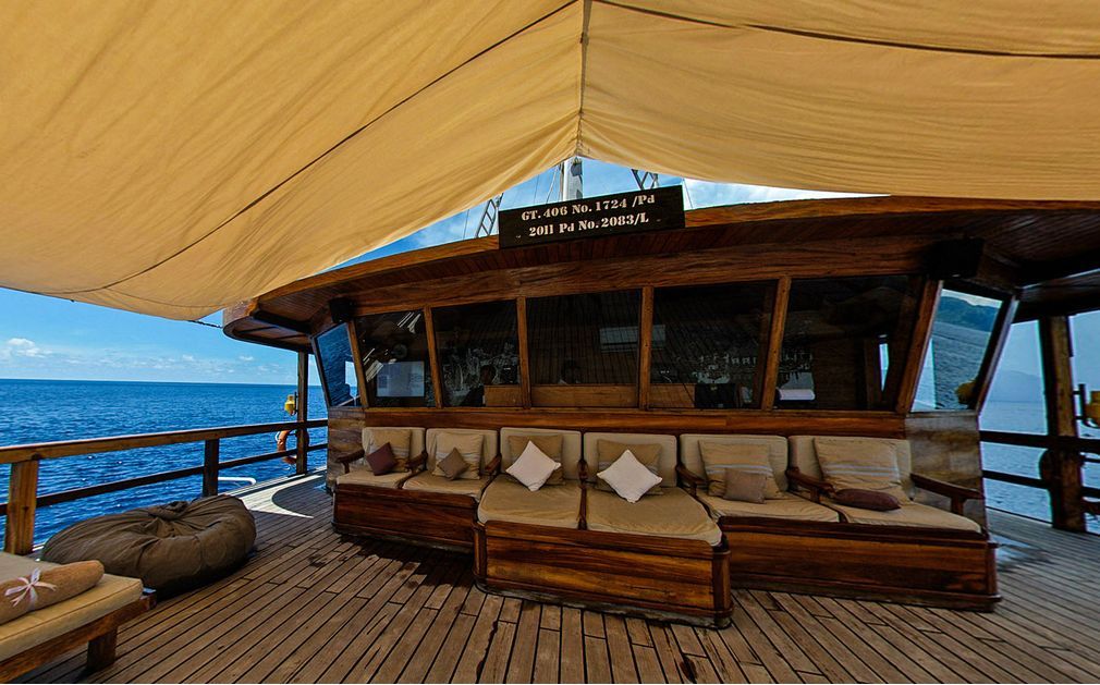 Wooden outdoor bar with seating and ocean view under a canvas canopy.