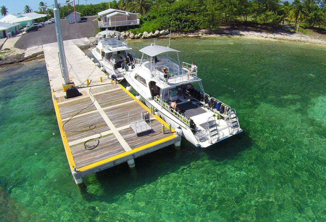 Two white boats docked at a pier in turquoise water.