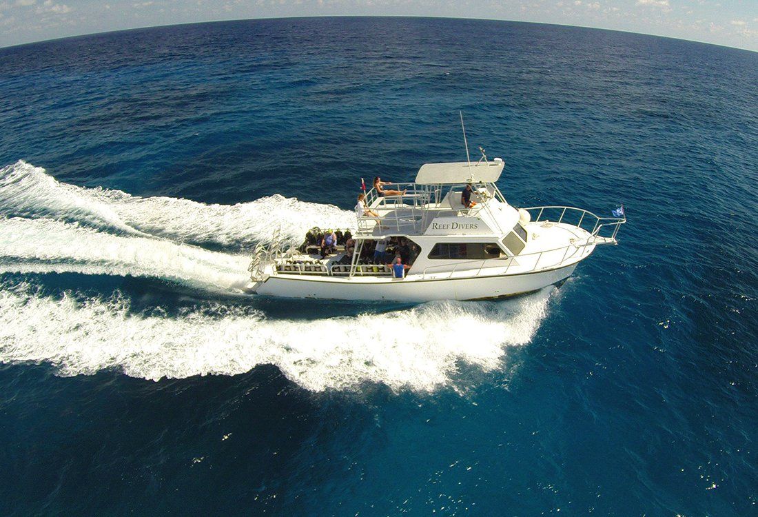 White boat speeding across blue ocean, creating a foamy wake.