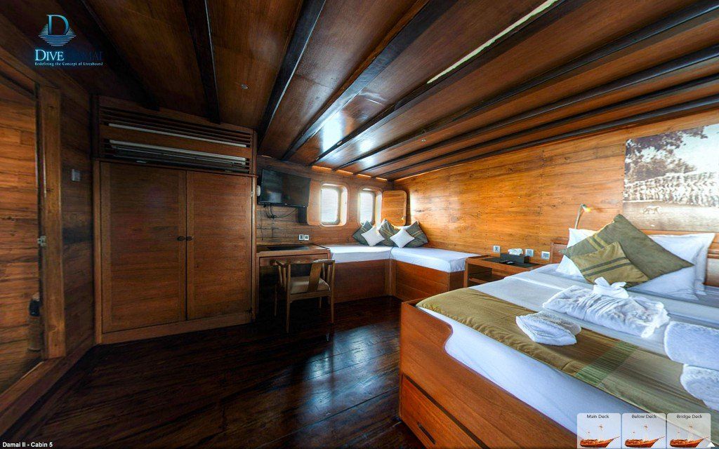 Wooden cabin interior with bed, seating area, and windows.