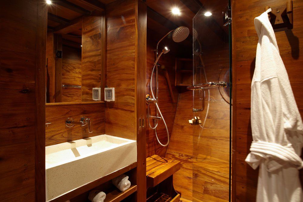 Wooden bathroom with shower, sink, and bathrobe. Brown walls, white sink, glass shower door.