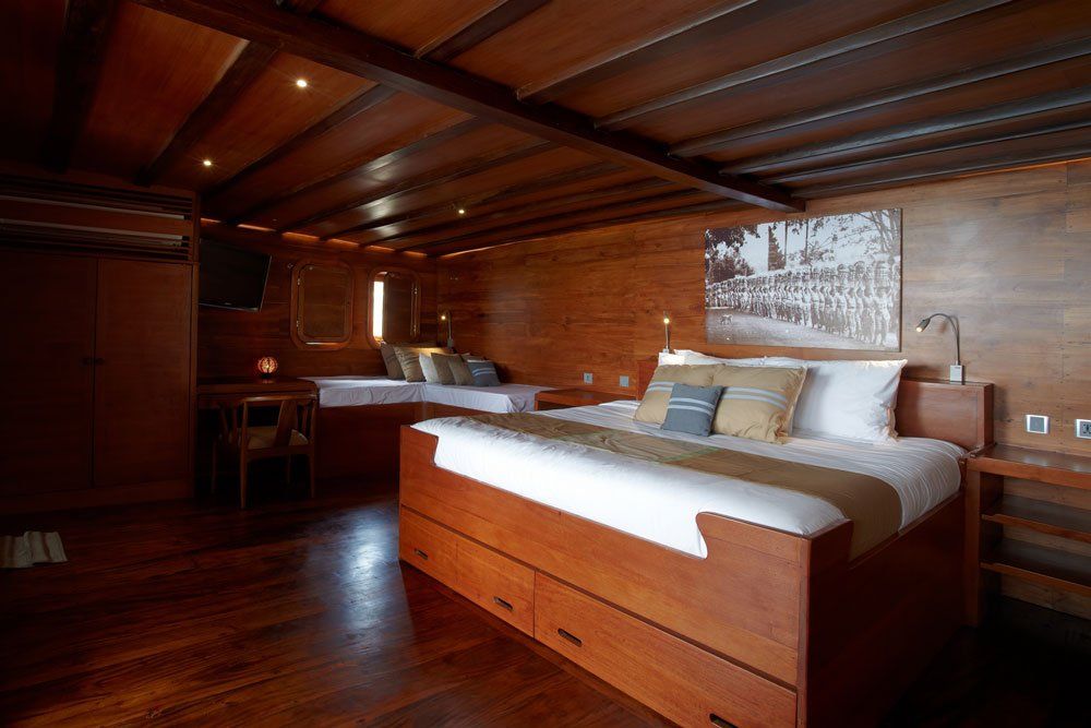 Wooden cabin interior with two beds, drawers, and art on the wall.