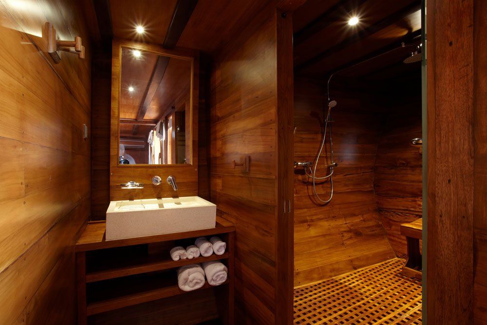 Wooden bathroom with a floating sink, large mirror, and open shower.