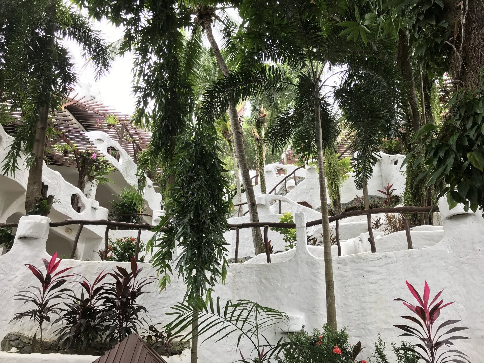 White stucco structures with wooden railings amidst lush greenery.