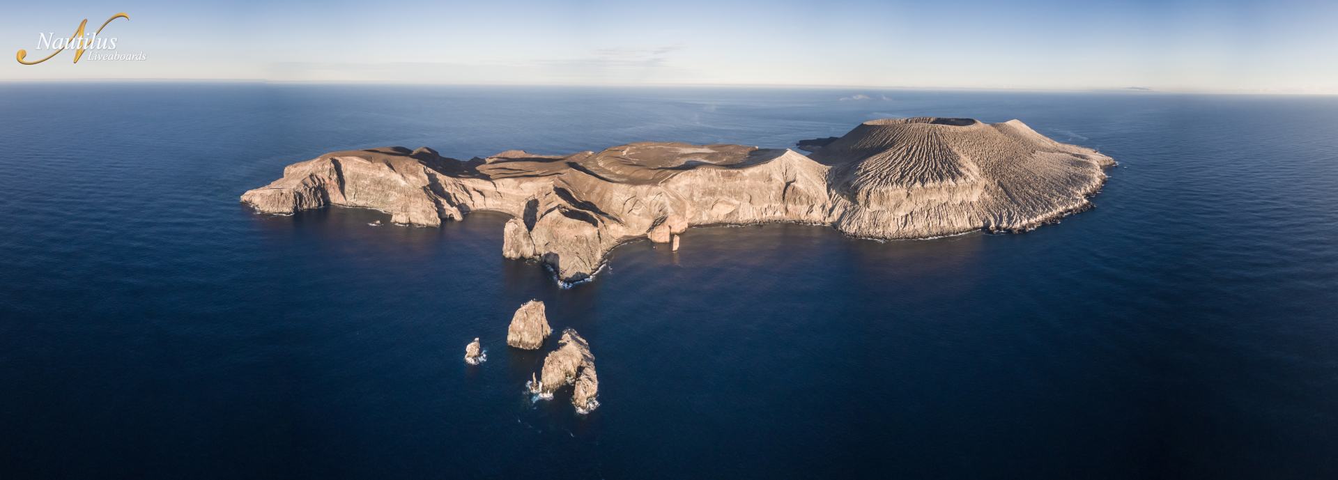 Aerial view of a rocky island in the ocean on a sunny day.