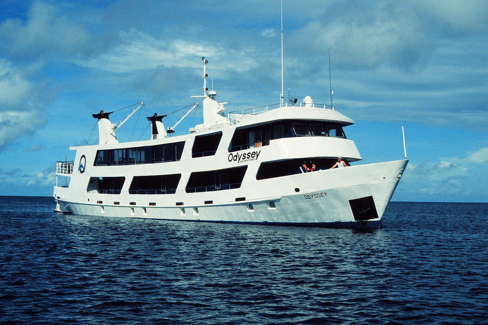 White boat floating on blue water under a cloudy sky.