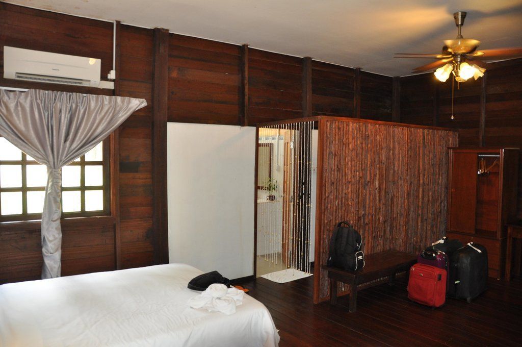Bedroom with wood walls, white bed, open bathroom, luggage.