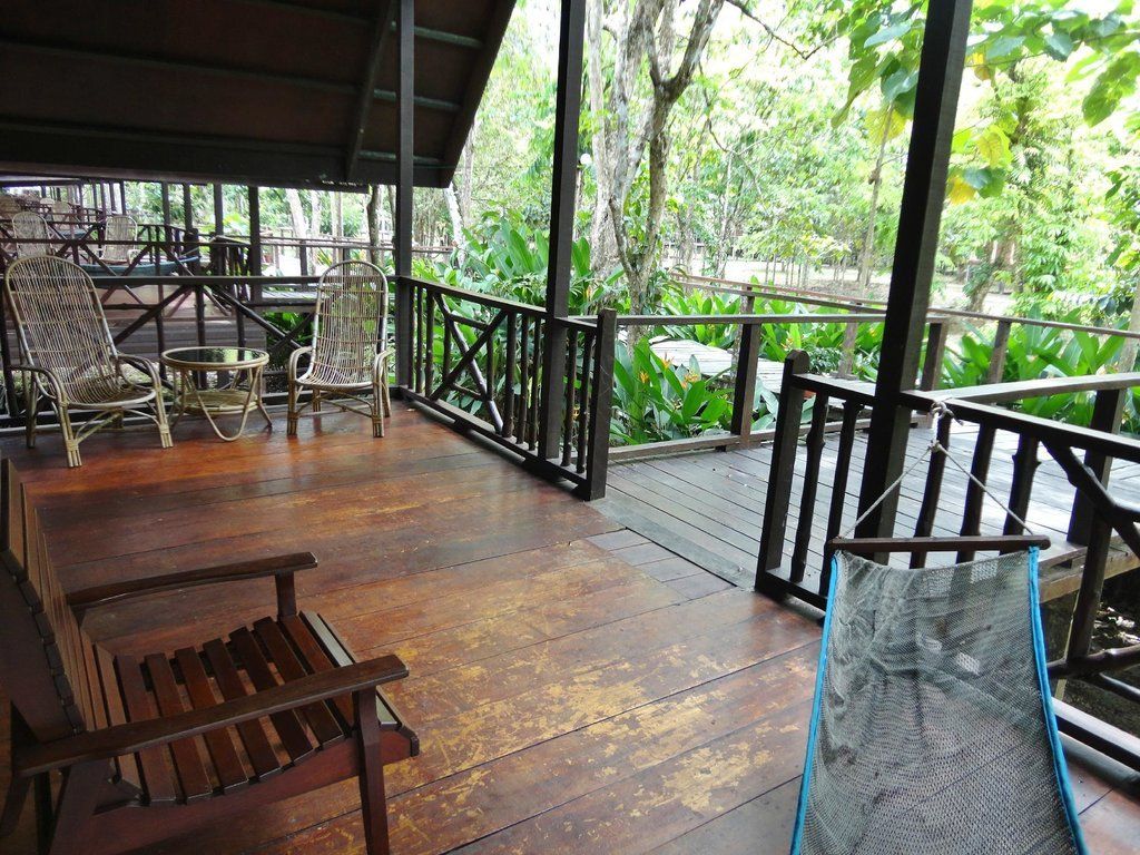 Wooden porch with seating overlooking lush greenery.