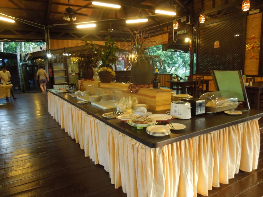 Buffet table in a restaurant setting, with food and a toaster. Pale yellow table skirt.