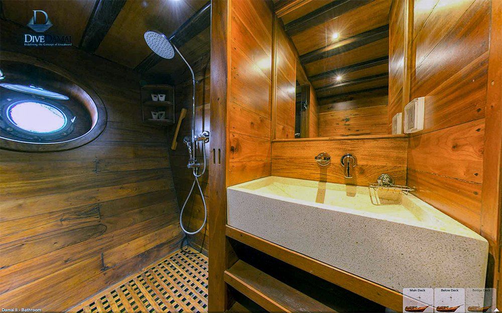 Wooden boat bathroom with shower, porthole, and stone sink.