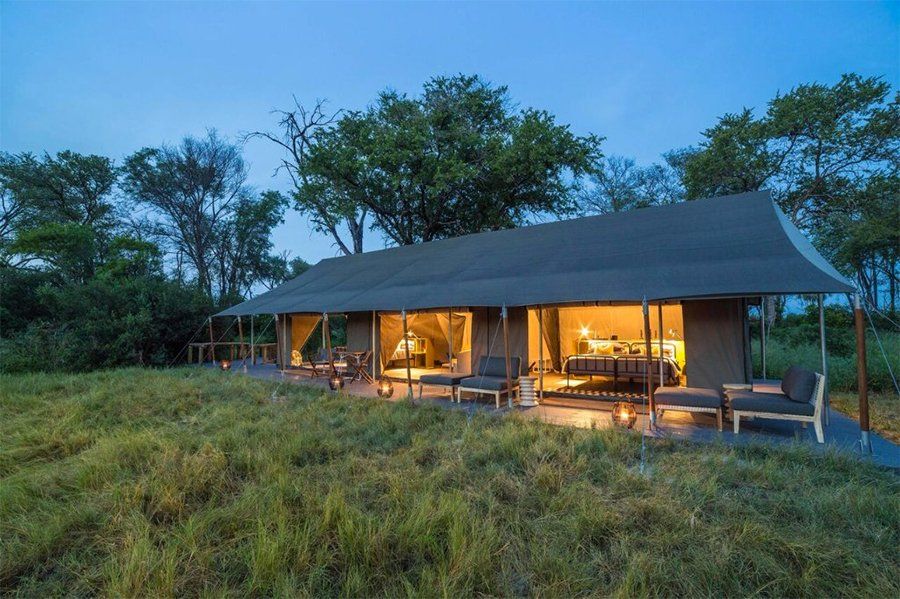 Safari tent with open front, chairs, and lit interior at dusk.