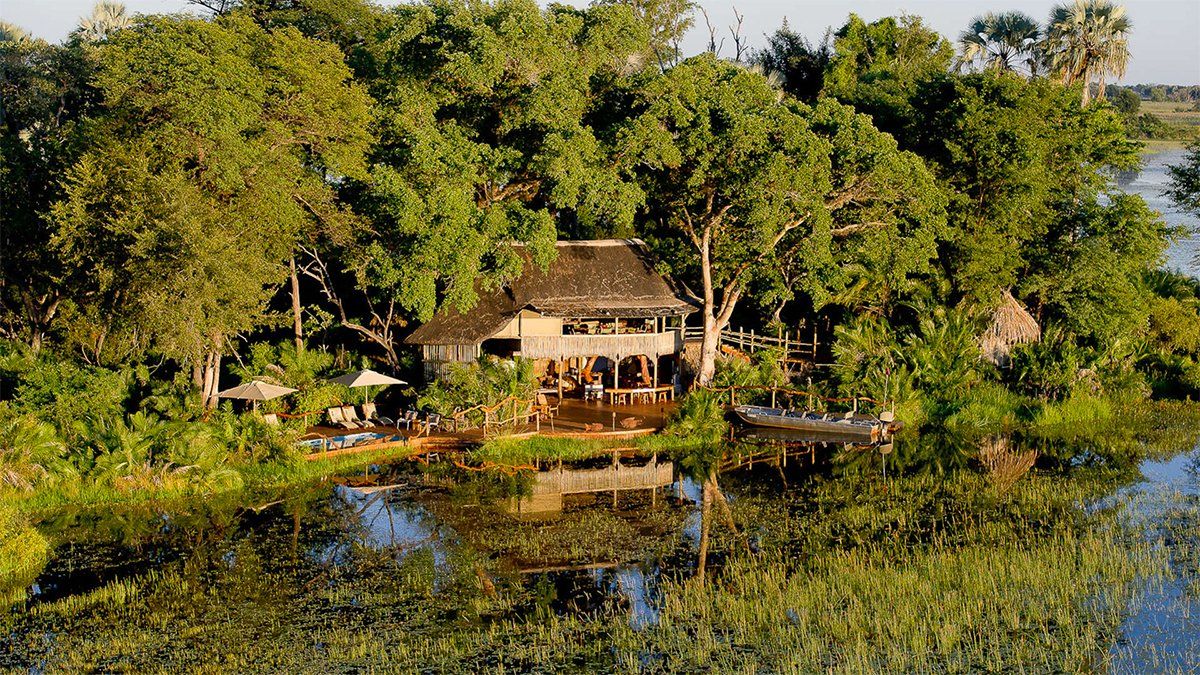 Lodge on a lush island, surrounded by water and trees.