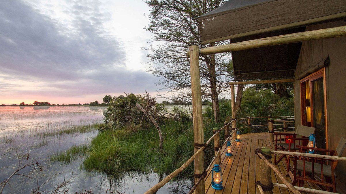 Wooden cabin porch overlooking flooded landscape at dusk.