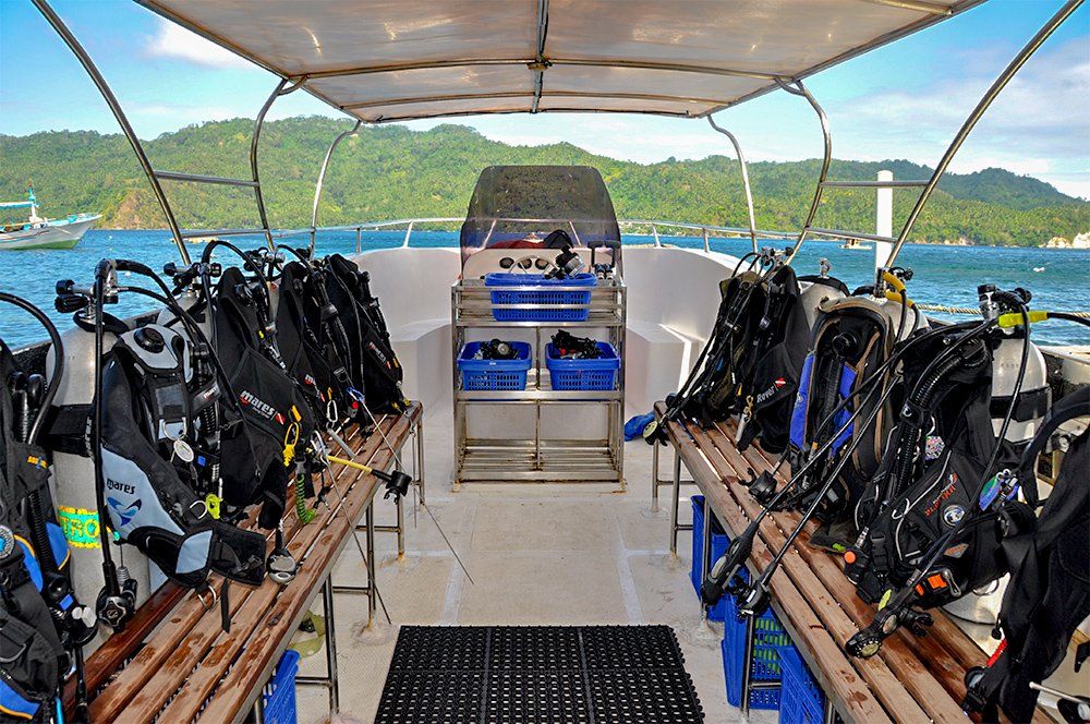 Scuba diving boat interior with equipment. Blue ocean, green island in the background.