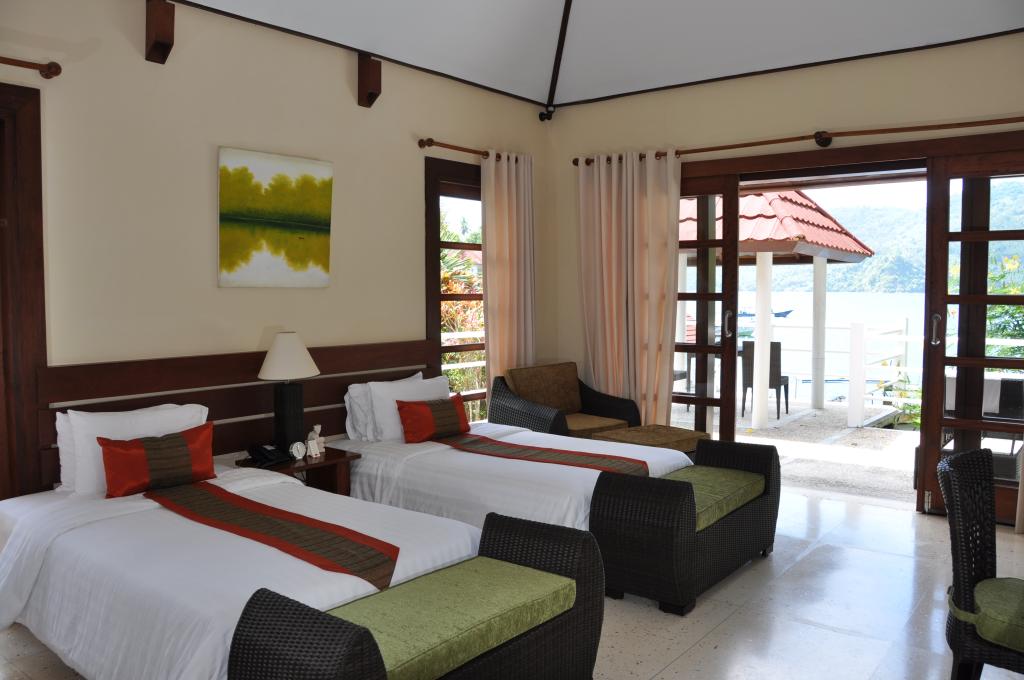 Bedroom with two twin beds, small seating area, and sliding doors to outdoor patio.