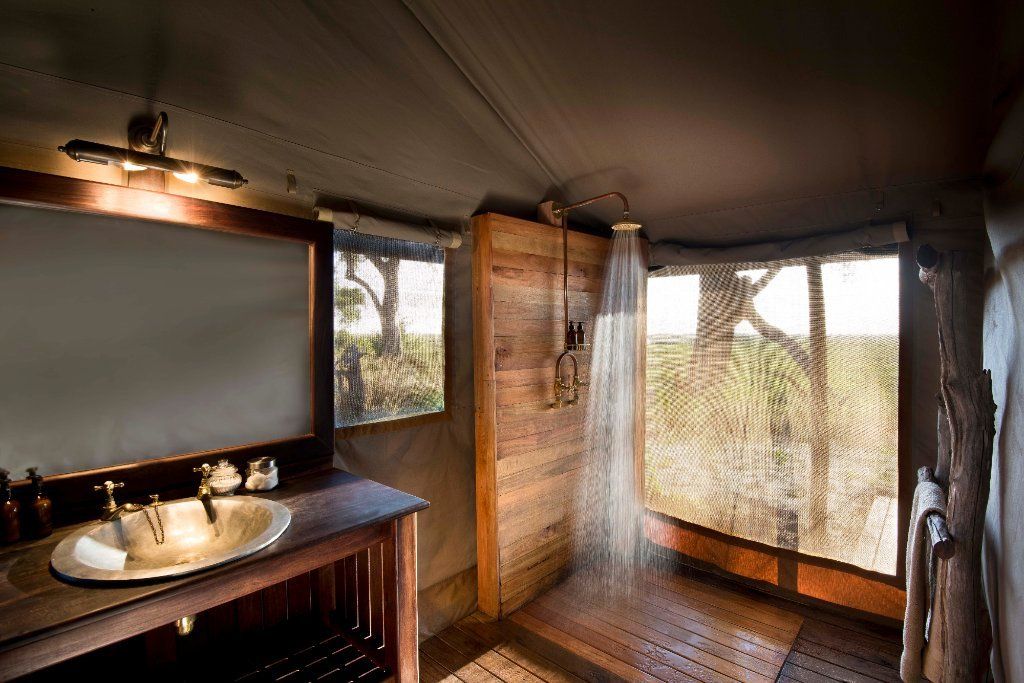 Bathroom with wooden features and a shower overlooking a natural landscape.