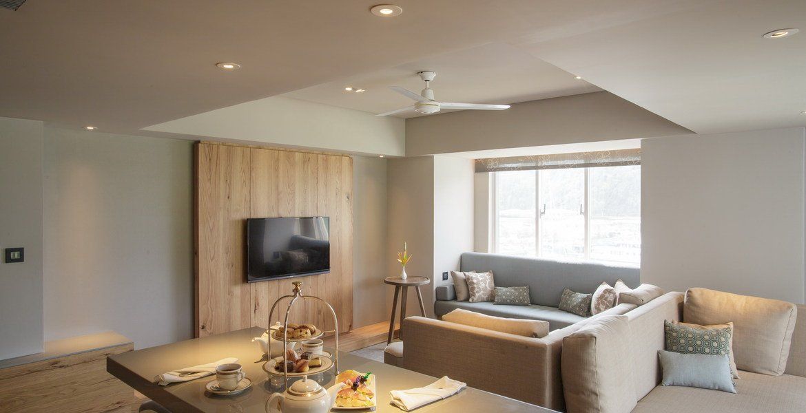 Living room with a gray sectional sofa, TV on a wood panel wall, and a kitchen island.