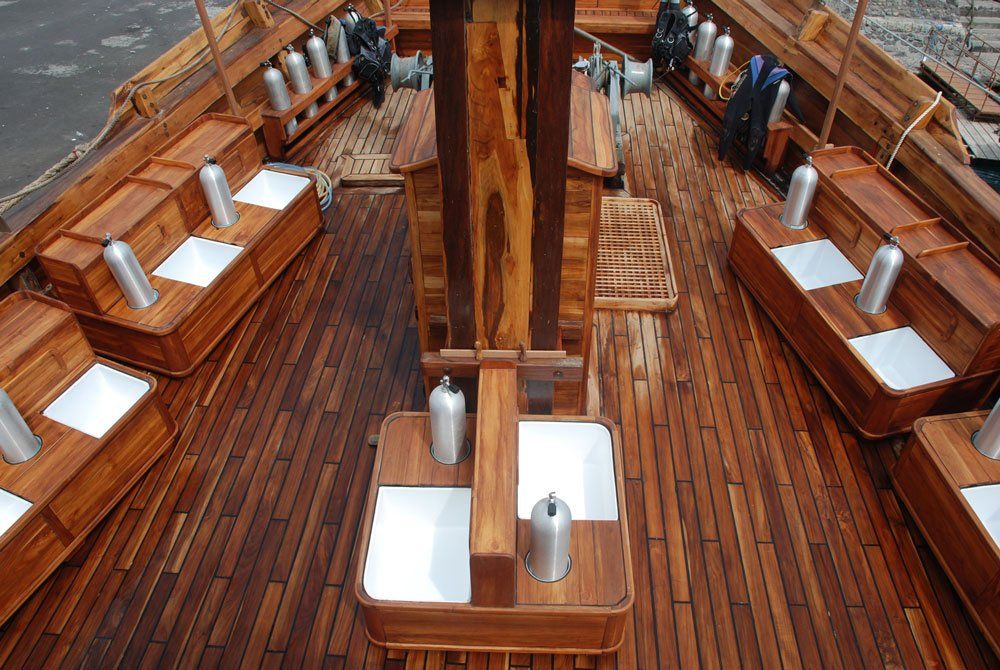 Wooden boat deck with dive tanks and seating.