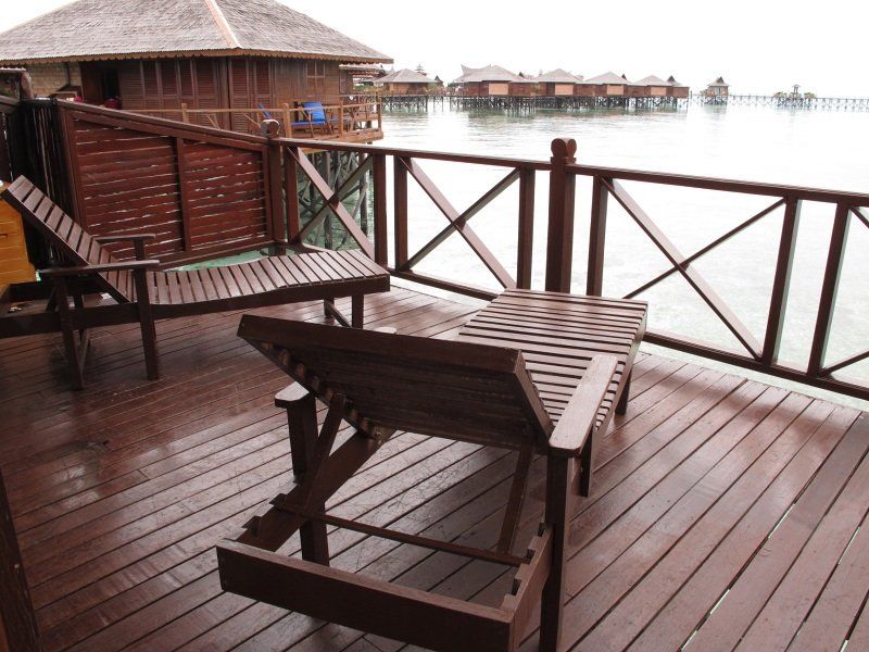 Wooden deck with lounge chairs overlooking overwater bungalows and the ocean.