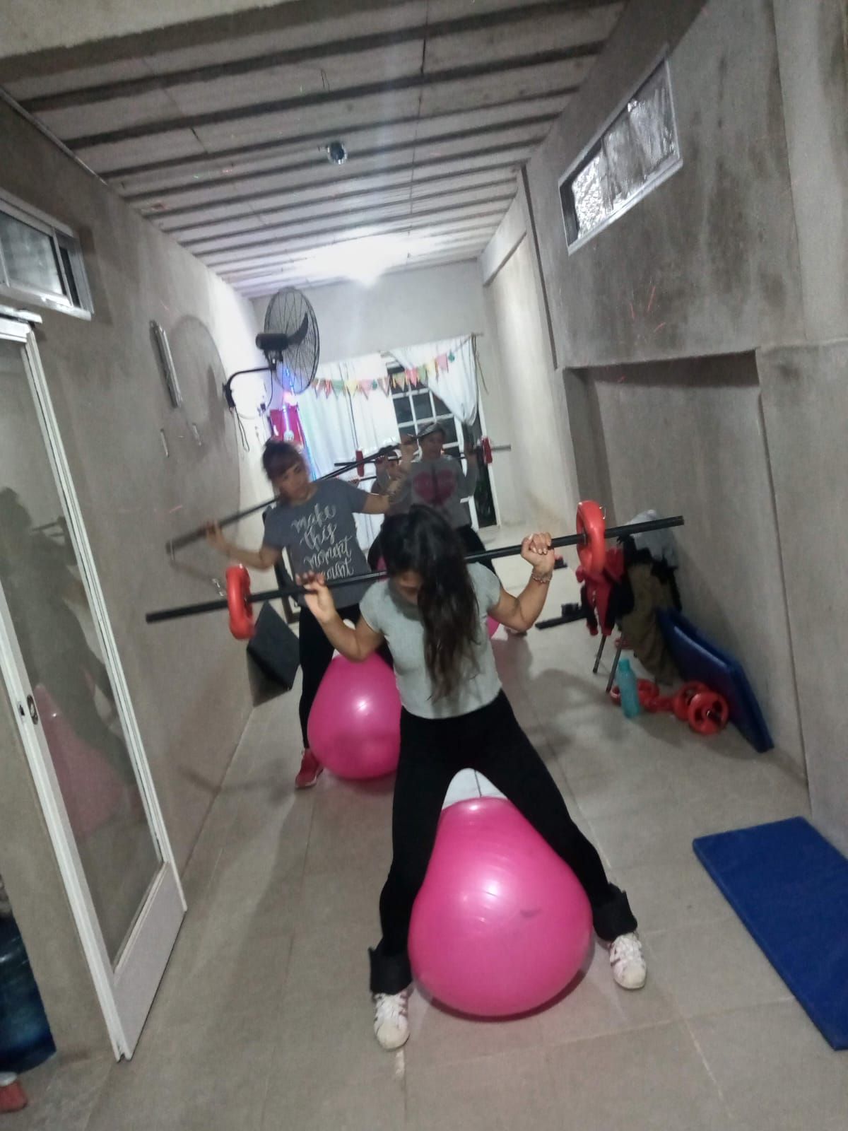 Personas en un gimnasio, haciendo ejercicio con pelotas de equilibrio y barras.