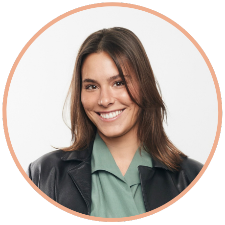 Smiling person wearing a sage green collared shirt and black leather jacket, set against a white background in a circle.