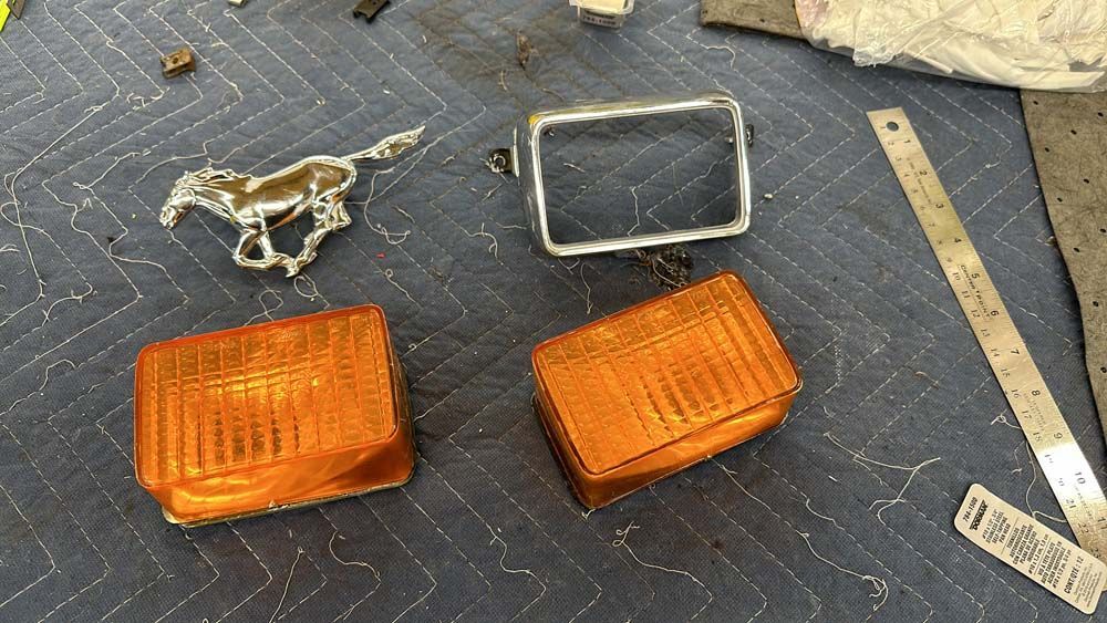 A mustang emblem is sitting on top of a table next to a pair of lights.