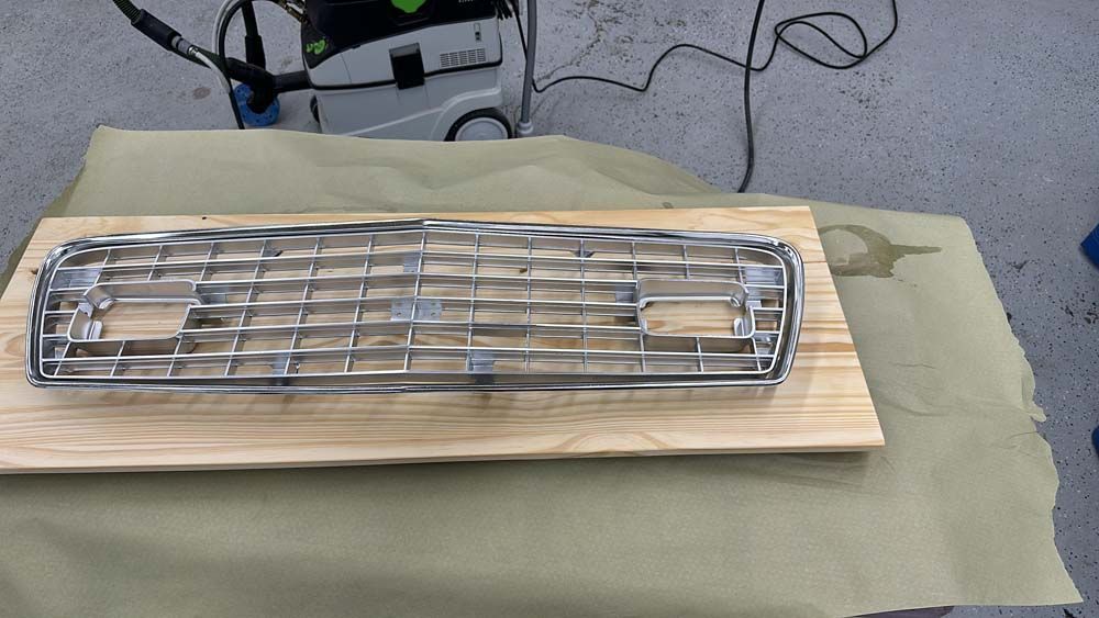 A metal grill is sitting on a wooden table next to a vacuum cleaner.