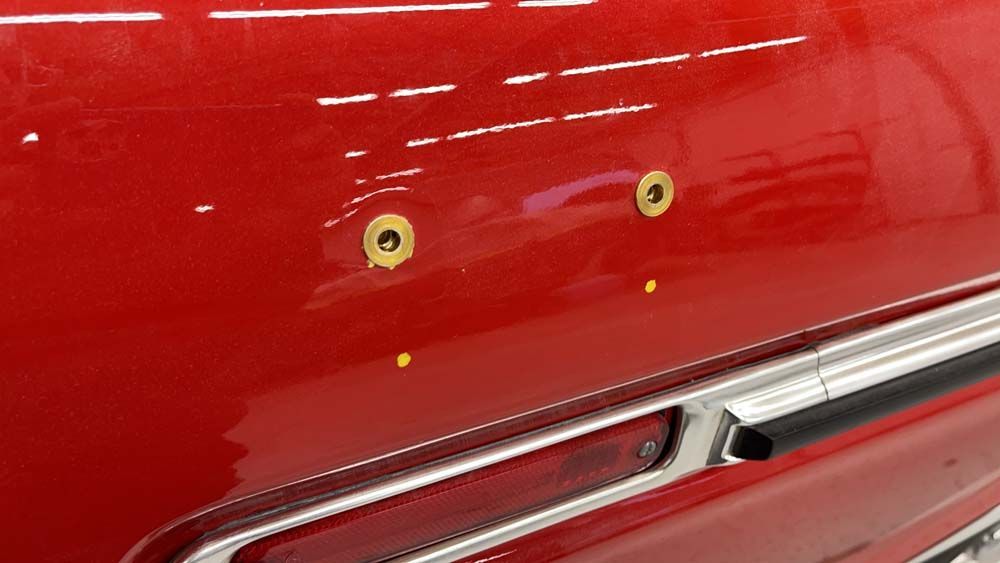 A close up of a red car with yellow spots on it.
