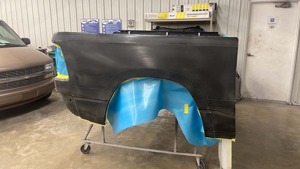 A truck bed is being painted in a garage.