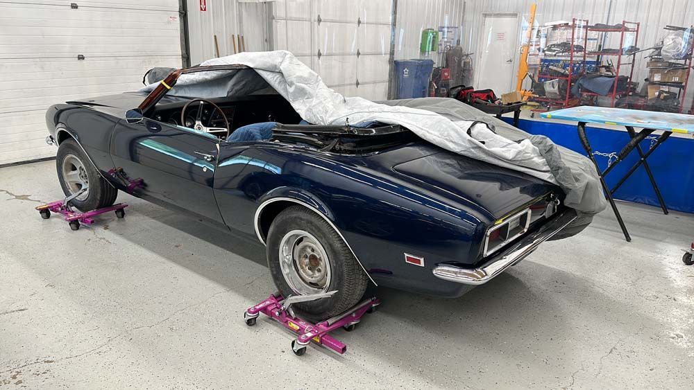 A blue car is sitting on wheels in a garage.