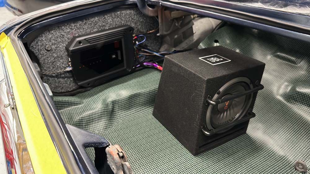 A subwoofer is sitting in the trunk of a car.