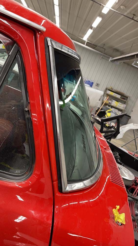 A red truck with a broken windshield is sitting in a garage.