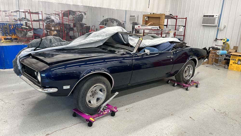 A blue car is sitting on wheels in a garage.