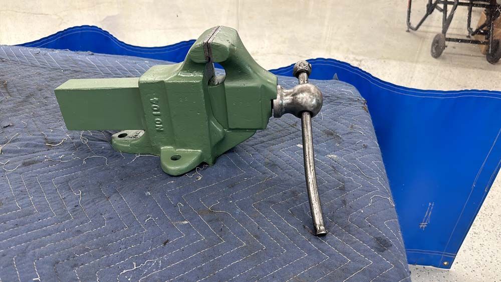 A green vise is sitting on top of a blue blanket.