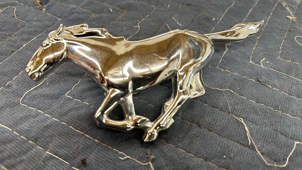 A silver horse emblem is sitting on a black blanket