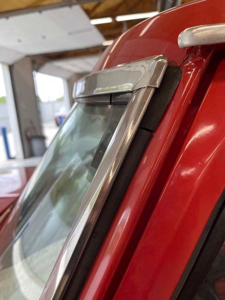 A close up of a red car 's windshield in a garage.