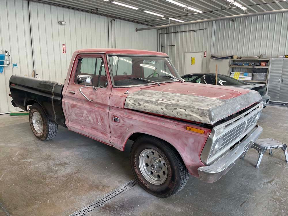 A pink pickup truck is parked in a garage.