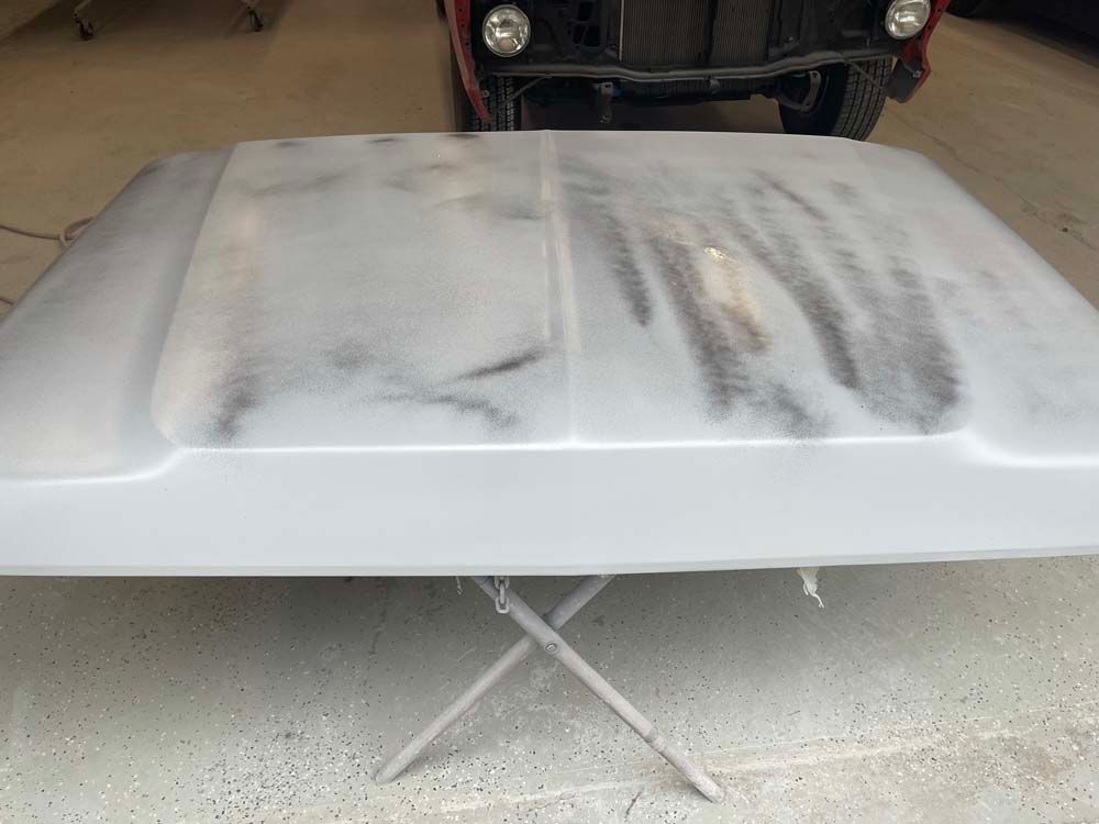 A hood is sitting on top of a table next to a jeep.