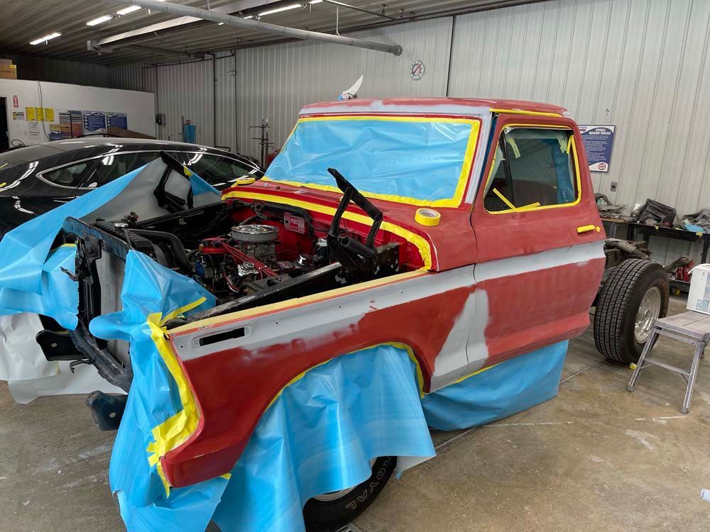 A red truck is being painted in a garage.